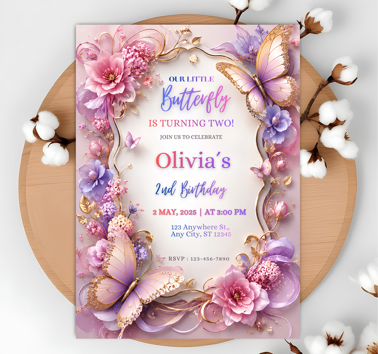 A square birthday invitation card with a pastel floral and butterfly design, styled flat on a round wooden tray with cotton bolls around it. The card reads 'Our Little Butterfly Is Turning Two! Olivia's 2nd Birthday' with pink, purple, lavender, and gold decorative elements.