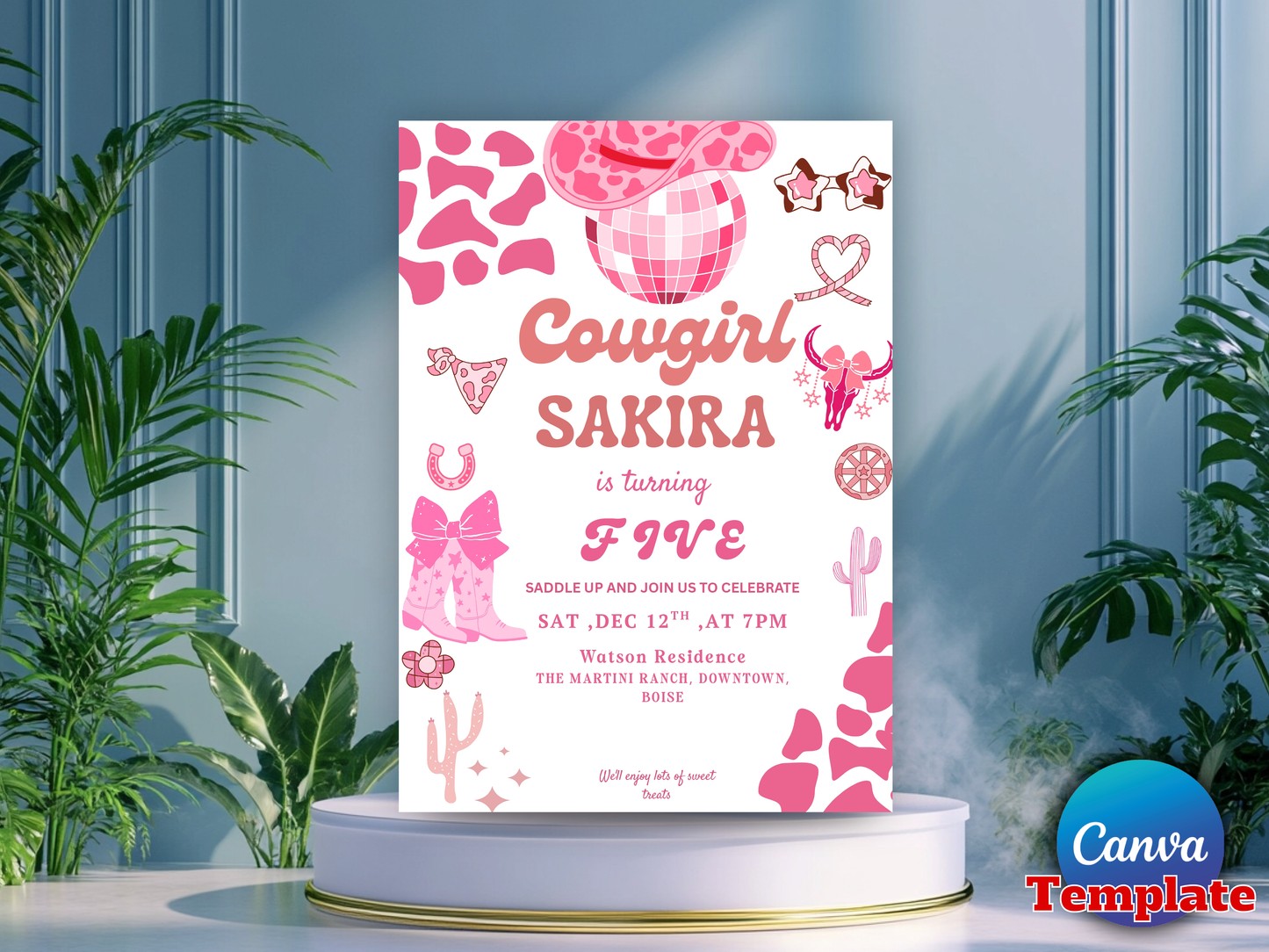 A pink and white 'Cowgirl Sakira' birthday invitation card displayed on a white pedestal with green plants in the background.